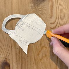 a person using scissors to cut out a piece of metal on a wooden table with wood planks