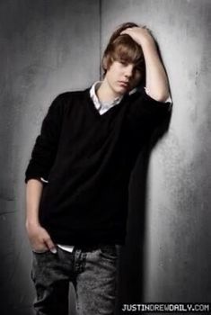 a young man leaning against a wall with his hand on his head