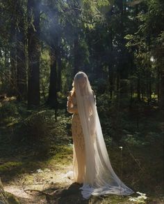 a woman is standing in the woods wearing a veil