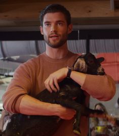 a man holding a small black animal in his right hand and looking at the camera