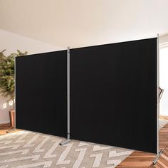 a room with two black screens in front of a rug and chair on the floor