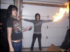 two people standing in front of a garage door with fire coming out of their arms