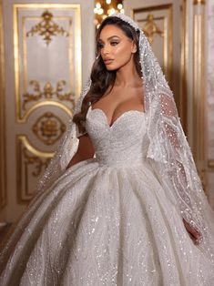 a woman in a wedding dress with long sleeves and a veil on her head is posing for the camera