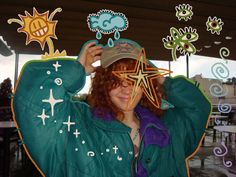 a woman with red hair wearing a green jacket and hat is holding up her star shaped stickers