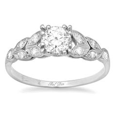 an antique style engagement ring with leaves and diamonds on the band, set in white gold