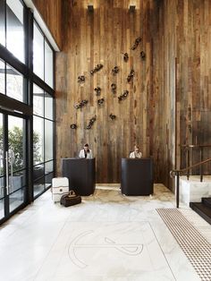 two black leather chairs in front of a wooden wall with sculptures on the walls and floor