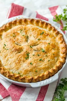 a baked pie in a white dish on a red and white checkered cloth