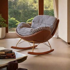 a living room with a rocking chair in front of a window and books on the floor