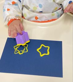 a toddler is playing with some rubber stamps on a blue piece of construction paper