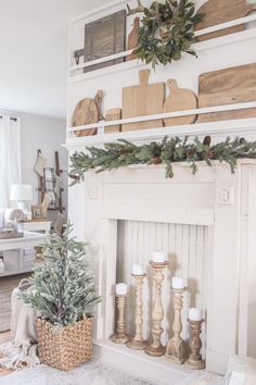 a white fireplace decorated for christmas with greenery and candles