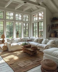 a living room filled with lots of white furniture and large windows in the ceiling area