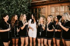 a group of women standing next to each other holding wine glasses in front of a building