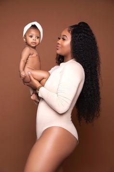 a woman holding a baby in her arms and wearing a white hat on top of her head