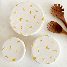 three wooden spoons sitting on top of a table next to two plates with banana print