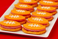 football cookies are arranged on a platter with orange frosting and white icing