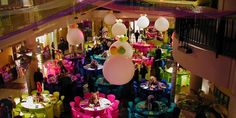 tables and chairs are set up for a party in a large room with balloons hanging from the ceiling