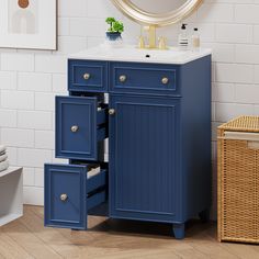 a bathroom vanity with blue drawers and a gold mirror on the wall next to it