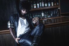 a man sitting in front of a bar wearing leather pants