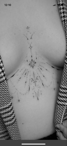 a black and white photo of a woman's breast with small tattoos on it