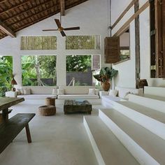 a living room filled with white furniture and lots of windows next to a wooden ceiling