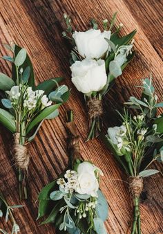 white flowers and greenery tied together on a wooden table