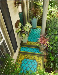 an image of a house with blue and yellow tiles on the ground, and plants in pots