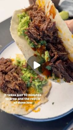 someone is holding up a taco with meat and guacamole