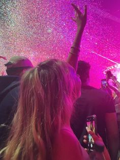 a group of people standing in front of a stage with their hands up to the sky