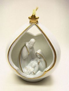 a white ornament with gold trimmings and a nativity scene in the center