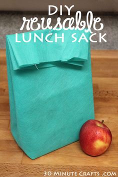 an apple sitting on top of a wooden table next to a green bag with the words diy reuseable lunch sack