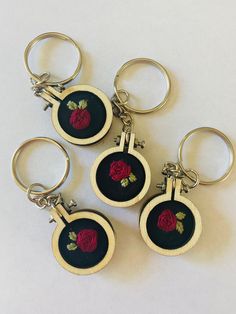 four embroidered keychains with roses on them sitting next to each other in front of a white background