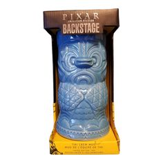 a blue tiki mug in a cardboard box on a white background with the words backstage printed on it