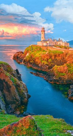 an island with a light house on top and water in the foreground at sunset