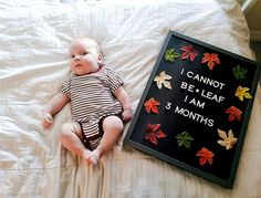 a baby laying on a bed next to a sign that says cannot be leaf i am 3 months