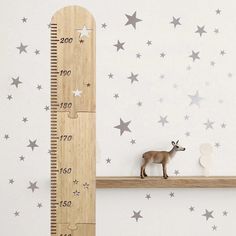 a wooden ruler sitting on top of a shelf next to a toy deer and star wall decals