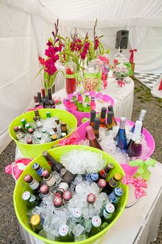 three buckets filled with bottles and ice on top of a table covered in flowers