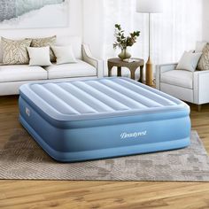 an inflatable mattress is sitting on the floor next to a couch and table