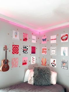 a bedroom with pink lights and pictures on the wall above the bed, along with a guitar