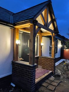 a small house with a black front door and wooden frame on the outside, lit up at night