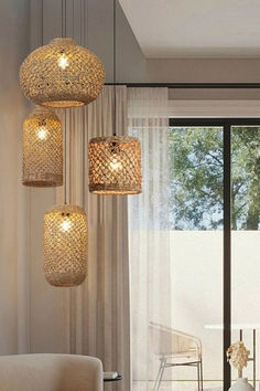 three lights hanging from the ceiling in a living room next to a chair and table