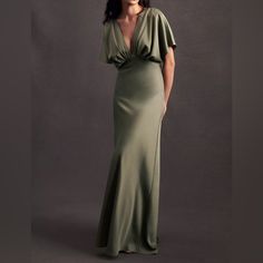 a woman in a long green dress posing for the camera with her hands on her hips