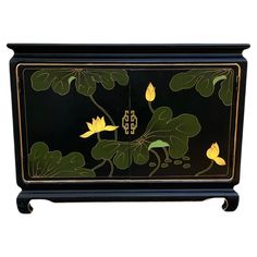 a black cabinet with yellow flowers and leaves painted on the front, sitting against a white background