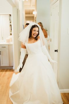 a woman in a white wedding dress is walking down the hall with her hands on her hips