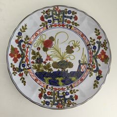 a decorative plate with birds and flowers painted on the front, sitting on a white surface