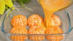 an orange being poured into a glass bowl filled with peeled oranges and other fruit