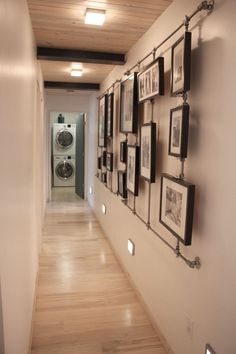 a long hallway with pictures on the wall and washer dryer in the background