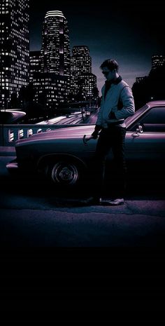 a man standing next to a parked car in front of a city skyline at night