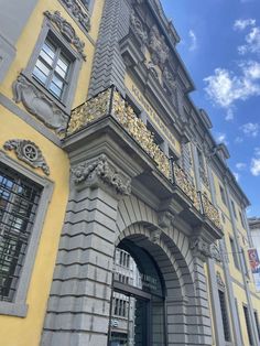 an old building with ornate gold and silver decorations on it's front door, under a blue cloudy sky