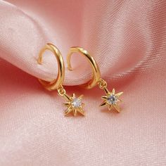 The cutest pair of huggie hoops glisten with a tiny dangling star. Available in gold or silver. Each star is adorned with a sparkly cz stone for some extra shine! Wear these in a first, second or third piercing to create a beautiful celestial ear stack. DETAILS - 14kt gold plated or sterling silver - cubic zirconia inlay - 12mm across Packaging + Delivery: All items come packaged in a cute Amanda Deer Jewelry box and are sent in a protective bubble mailer. If ordering multiple pieces, please let Celestial Style Huggie Earrings With Star Charm, Celestial Star-shaped Huggie Earrings With Star Charm, Celestial Huggie Earrings With Star Charm Dangle, Celestial Dangle Huggie Earrings With Star Charm, Dainty Gold Star Huggie Earrings, Gold Star Charm Hoop Earrings, Gold Star Huggie Earrings In Celestial Style, Gold Star Celestial Huggie Earrings, Gold Star-shaped Celestial Huggie Earrings