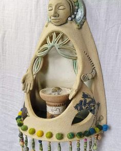 a ceramic sculpture of a woman with her eyes closed, holding a cup and smiling